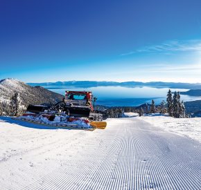 snow cat grooming skiing trail with views of lake tahoe