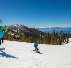 mom snowboards behind skier son with lake tahoe views at diamond peak