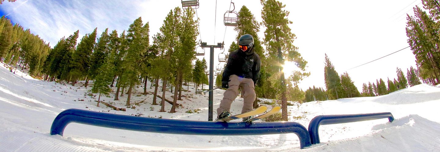 skier rides a rail in village terrain park