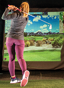 woman hits a golf ball playing virtual indoor golf at the incline village championship golf shop