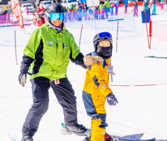 ski instructor with child wearing yellow ski outfit