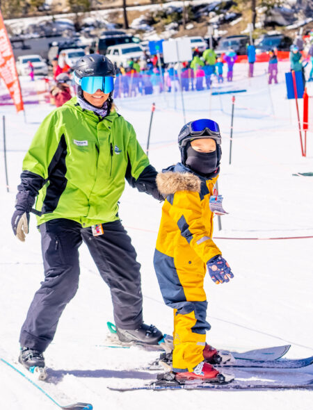 ski instructor with child wearing yellow ski outfit