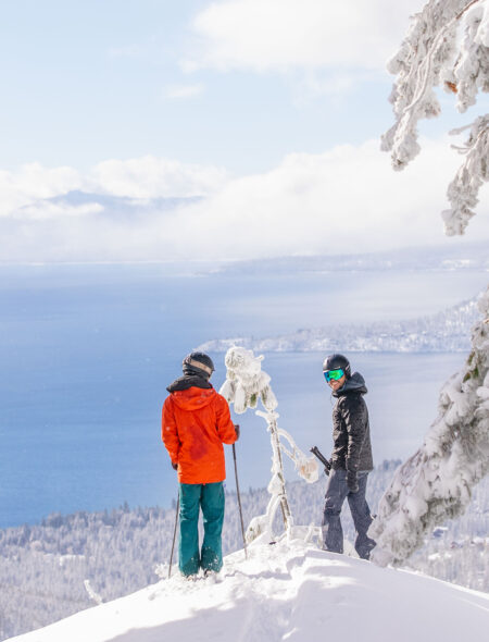 two male skiers looking at views of lake tahoe in the powder