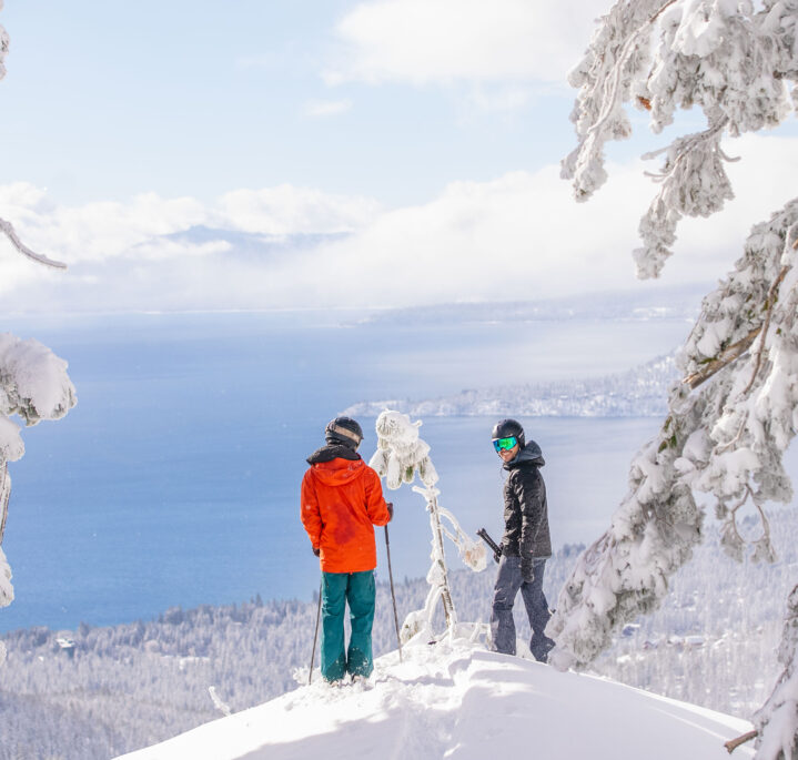 two male skiers looking at views of lake tahoe in the powder