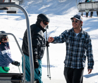 male lift operator reaches for chairlift at diamond peak ski resort