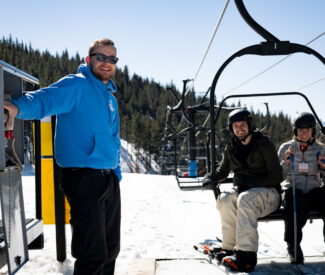 male lift operator smiles as couple gets off chairlift at diamond peak ski resort