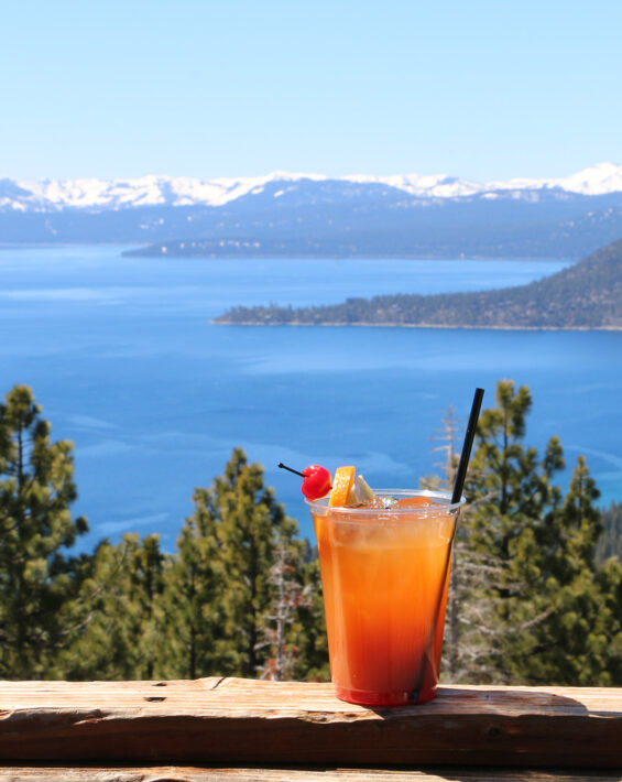 orange cocktail on snowflake deck railing with lake view