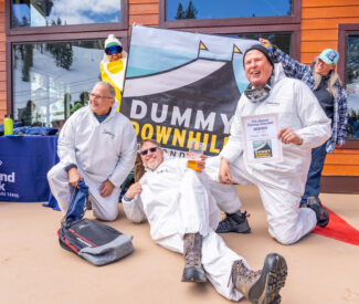 three men pose with dummy downhill banner