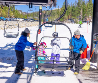 female and male lift operator hold chair for skiers