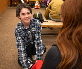 young boy employee in rental shop with ski boots