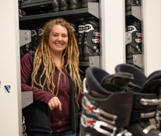 female employee in rental shop with ski boots