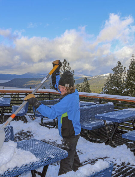 employee shovels snow on deck