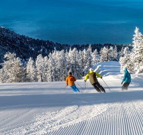 three skiers with views of Lake Tahoe