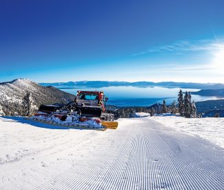 snow cat grooming skiing trail with views of lake tahoe