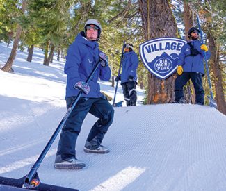 terrain park staff poses with rake in the diamond peak village terrain park