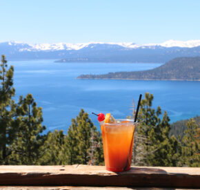 orange cocktail on snowflake deck railing with lake view