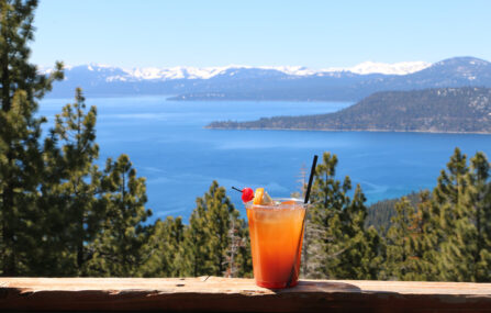 orange cocktail on snowflake deck railing with lake view