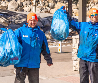 male employees smile with bags of trash