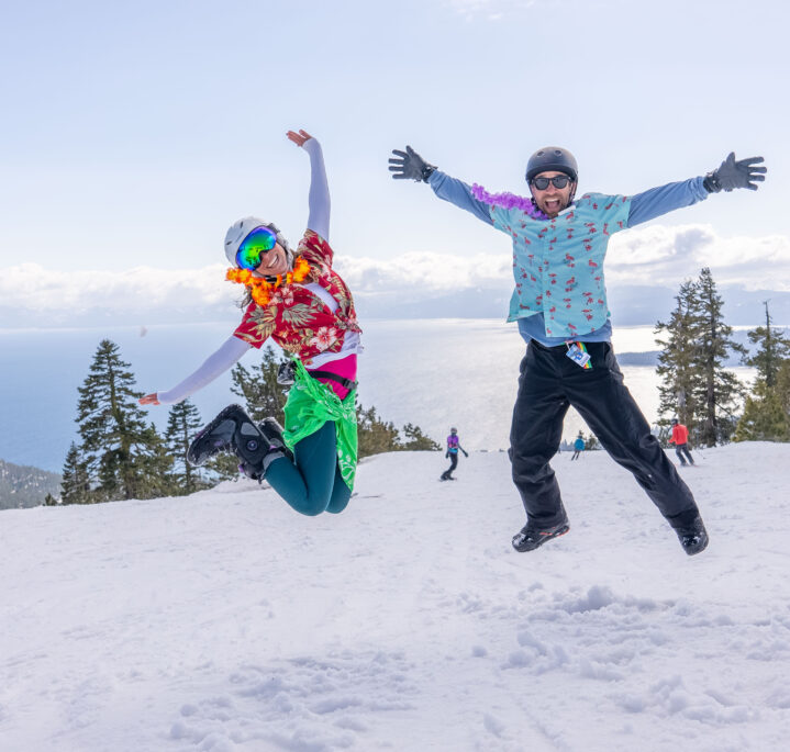 woman and man jump on top of mountain in tropical tees
