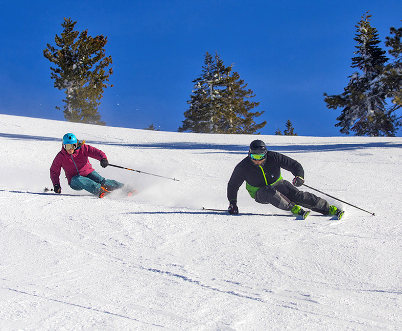 two skiers carving a groomer at diamond peak