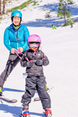 mom and daughter ski down the slopes